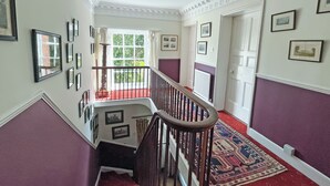 A staircase with a handrail, a red carpet, and a view of the outdoors through a window. - 8 bedroom accommodation in Horbling, near Sleaford (Horbling, near Sleaford)