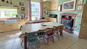 A kitchen with a dining table, chairs, a sink, cabinets, a microwave, a kettle, and a brick oven. - 8 bedroom accommodation in Horbling, near Sleaford (Horbling, near Sleaford)