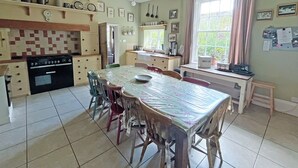 A kitchen with a dining table, chairs, a stove, and a window with curtains. - 8 bedroom accommodation in Horbling, near Sleaford (Horbling, near Sleaford)