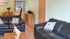 A living room with two black leather sofas, a wooden coffee table, and a wooden cabinet. - 3 bedroom accommodation in Oban (Oban)