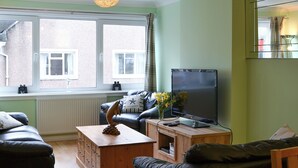 A living room with a sofa, a coffee table, a TV, and a window with curtains. - 3 bedroom accommodation in Oban (Oban)