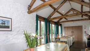 Een eetgedeelte met een tafel, stoelen, een vaas met bloemen en een keuken op de achtergrond.