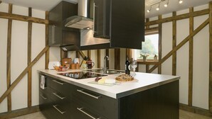 Une cuisine moderne dotée d’un îlot central, de poutres en bois et d’une grande fenêtre.