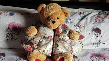 A teddy bear sitting on a bed with a floral patterned bedspread.