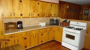 A kitchen with wooden cabinets, a stove, a toaster, and a coffee maker. - 5 Bedroom Pet Friendly House Lake George Region (Johnsburg)