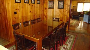 A dining room with a wooden table and chairs, framed pictures on the walls, and a chandelier. - 5 Bedroom Pet Friendly House Lake George Region (Johnsburg)