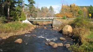 A river with a bridge, surrounded by trees and rocks. - 5 Bedroom Pet Friendly House Lake George Region (Johnsburg)