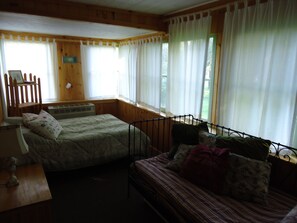 Habitación con dos camas, cabecero de madera, un escritorio y una ventana con cortinas.