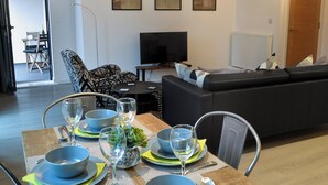 A dining area with a table set for four, a sofa, a TV, and framed artwork on the wall. - 2 bedroom accommodation in Alnwick (Alnwick)