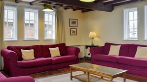 A room with two purple sofas, a glass-top coffee table, and a lamp on a side table. - 6 bedroom accommodation in Attingham Park, near Shrewsbury (Attingham Park, near Shrewsbury)