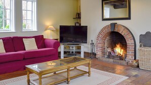 A living room with a brick fireplace, a television, a sofa, and a coffee table. - 6 bedroom accommodation in Attingham Park, near Shrewsbury (Attingham Park, near Shrewsbury)