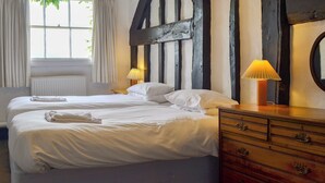 A hotel room with two beds, a wooden wall, a window with curtains, and a dresser with a lamp. - 6 bedroom accommodation in Attingham Park, near Shrewsbury (Attingham Park, near Shrewsbury)