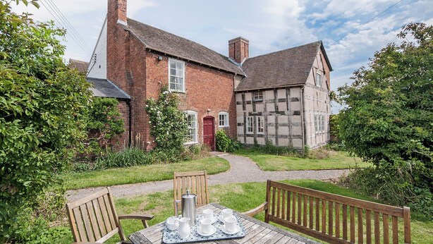 A traditional half-timbered house with a red door and a brick chimney. - 6 bedroom accommodation in Attingham Park, near Shrewsbury (Attingham Park, near Shrewsbury)