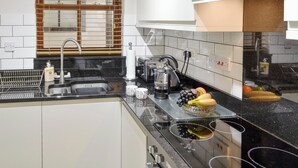 Een moderne keuken met een spoelbak, kookplaat en diverse apparaten.