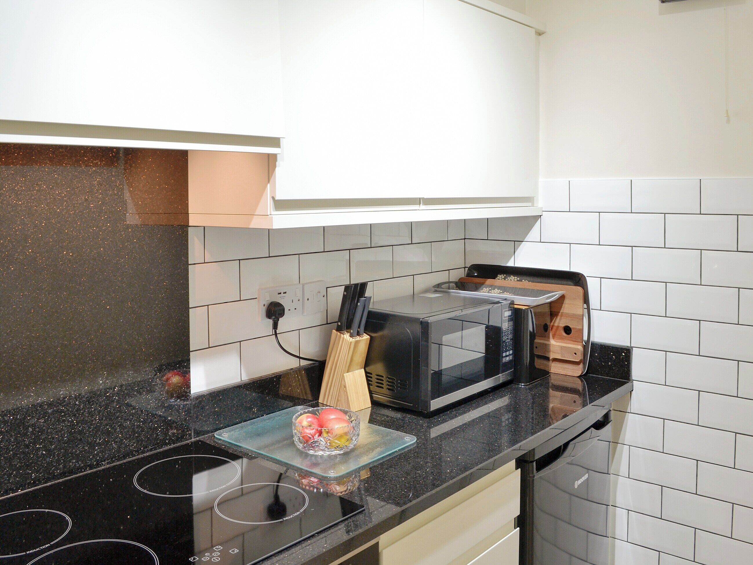 Eine Küche mit schwarzem Arbeitsplatz, einer Mikrowelle, einem Toaster und einem Messerblock.