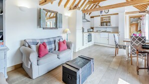 A cozy living room with a sofa, a wooden ceiling, and a kitchen area with cabinets and a dining table. - 1 bedroom accommodation in Battle (Battle)