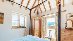A bedroom with a bed, wooden wardrobe, and a window with a view of trees. - 1 bedroom accommodation in Battle (Battle)