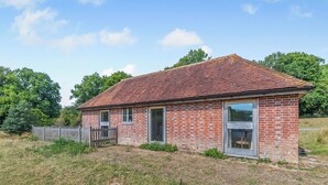 A brick building with a tiled roof, a wooden fence, and a grassy area in front. - 1 bedroom accommodation in Battle (Battle)