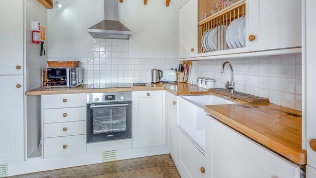A kitchen with white cabinetry, wooden beams, a Bosch oven, and a sink with a wooden countertop. - 1 bedroom accommodation in Battle (Battle)