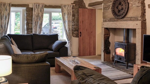 A cozy living room with a stone fireplace, a sofa, a wooden coffee table, and a lamp.