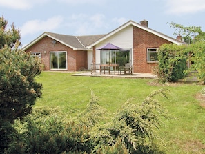 Een tweelaags bakstenen huis met een terras en een schuifdeur.