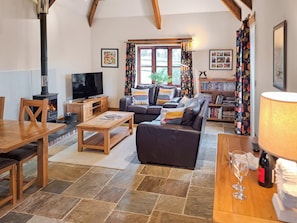 A cozy living room with a fireplace, a sofa, a TV, a bookshelf, and a dining area.