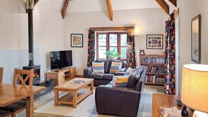 Ein gemütliches Wohnzimmer mit Kamin, einer Couch, einem Fernseher, einem Bücherregal und einem Essbereich.