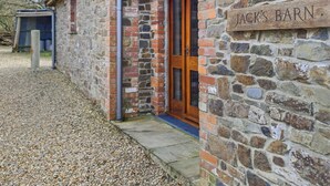 Ein Steinhaus mit einer Holztür und einem Schild, auf dem 'JACK'S BARN' steht.