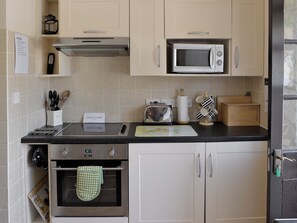 Eine Küche mit Mikrowelle, Toaster, Backofen und verschiedenen Kochutensilien.