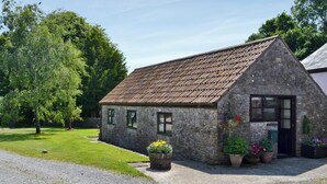 A stone building with a sloped roof, a door, and windows. There are potted plants in front of the building. - 1 bedroom accommodation in Priddy, near Wells (Priddy, near Wells)