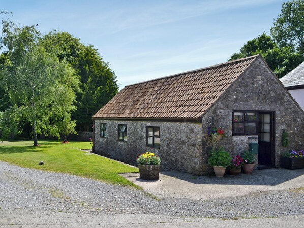 A stone building with a sloped roof, a door, and windows. There are potted plants in front of the building. - 1 bedroom accommodation in Priddy, near Wells (Priddy, near Wells)