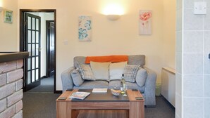 A living room with a grey sofa, a wooden coffee table, and a fireplace. - 1 bedroom accommodation in Priddy, near Wells (Priddy, near Wells)