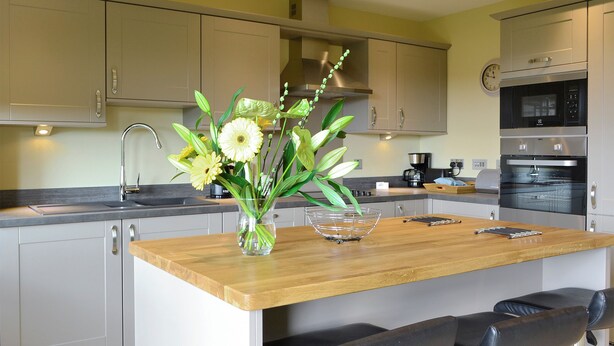 A modern kitchen with a central island, bar stools, a coffee machine, and a clock on the wall. - 2 bedroom accommodation in Linlithgow, near Edinburgh (Linlithgow, near Edinburgh)