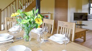 A dining table set with white plates, bowls, and wine glasses, a vase with flowers, and wooden chairs. - 2 bedroom accommodation in Linlithgow, near Edinburgh (Linlithgow, near Edinburgh)