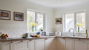 A modern kitchen with white cabinets, a built-in oven, and a window with a view of trees. - 4 bedroom accommodation in Taynuilt, near Oban (Taynuilt, near Oban)