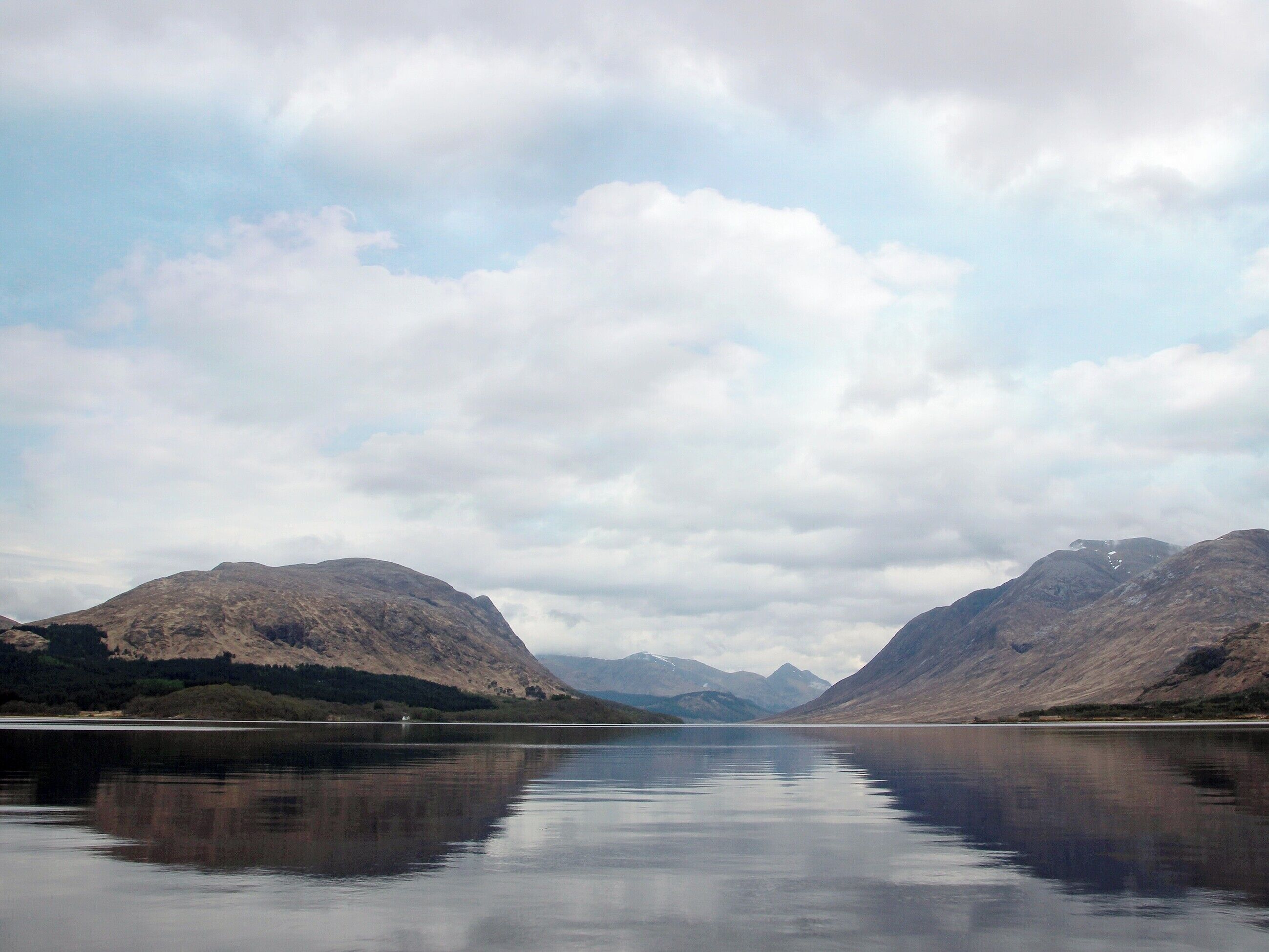 A calm lake with mountains in the background.