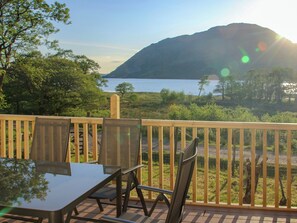 A deck with a table and chairs overlooking a lake and mountains. - 4 bedroom accommodation in Taynuilt, near Oban (Taynuilt, near Oban)