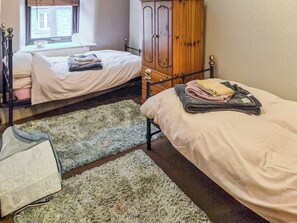 Une chambre avec deux lits, une armoire, un radiateur et une fenêtre.