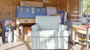 L’intérieur chaleureux d’un chalet avec un fauteuil à rayures, des murs en bois, une valise ancienne et divers objets disposés sur des étagères.