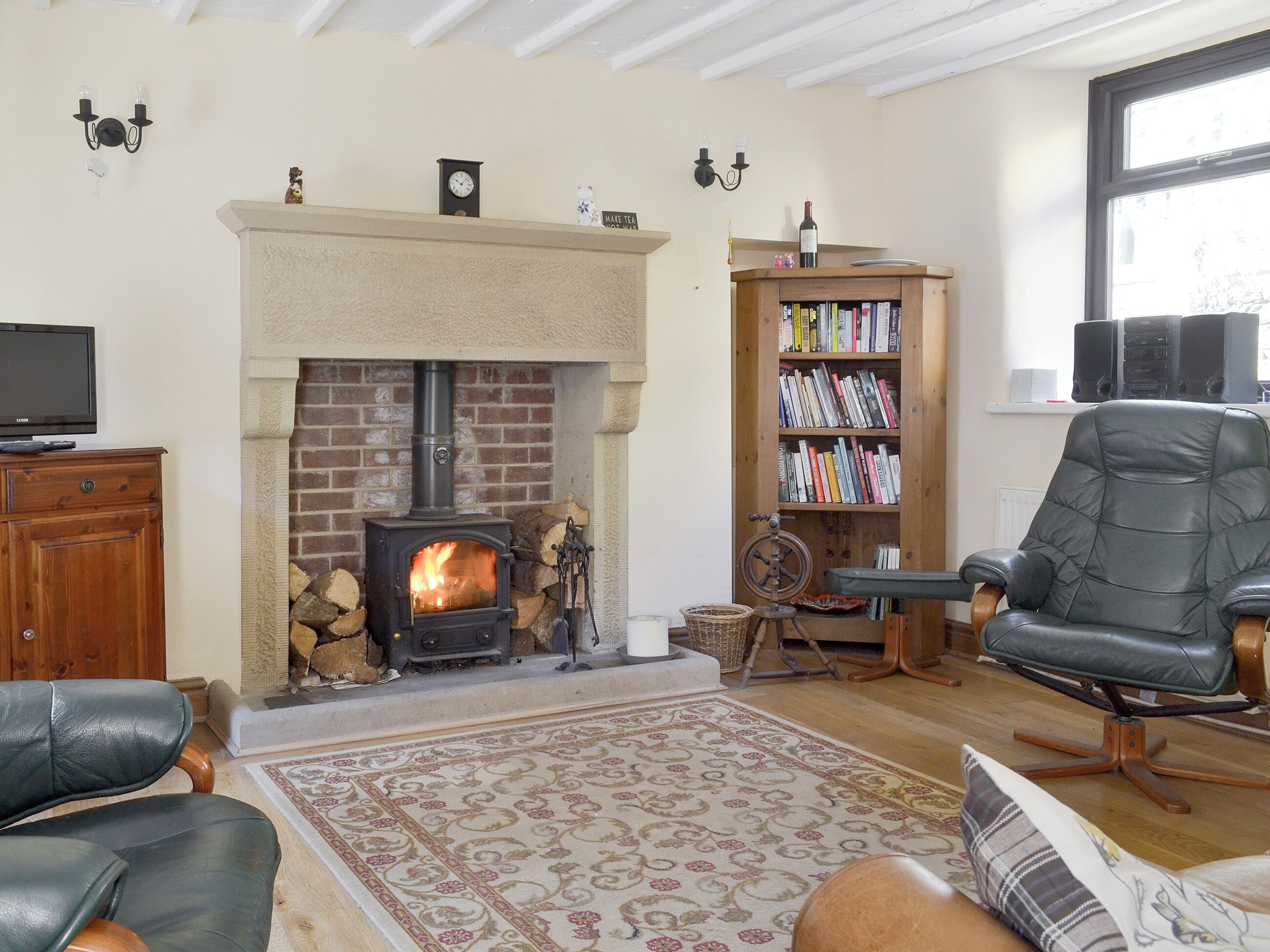 Ein gemütliches Wohnzimmer mit Kamin, Bücherregal, Ledersessel und Fernseher.