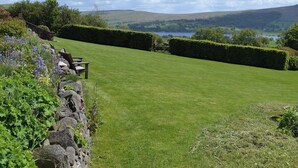 A well-maintained lawn with stone walls and benches, offering a view of a lake and hills in the distance. - 1 bedroom accommodation in Watermillock-on-Ullswater (Watermillock-on-Ullswater)