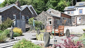 A stone building with a garden area featuring a wooden bench and a sign that reads "NEW TO THE AREA". - 1 bedroom accommodation in Watermillock-on-Ullswater (Watermillock-on-Ullswater)