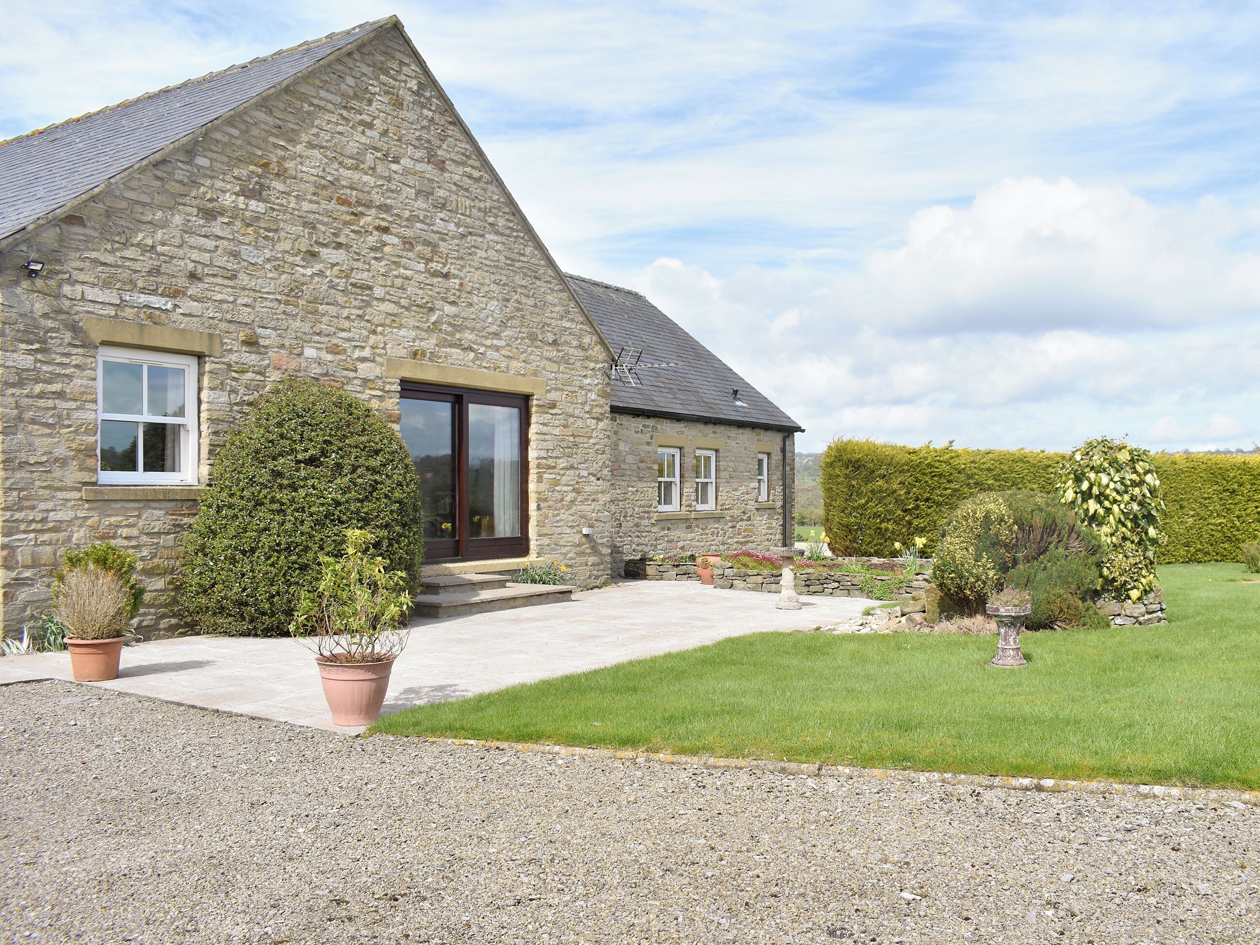 A stone house with a sloped roof, a front door, and a small porch area.