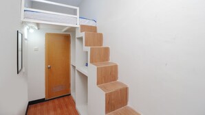 A compact room with a bunk bed, a wooden staircase, and a door. - Kamar Keluarga Bandara Mas Syariah (Tangerang)