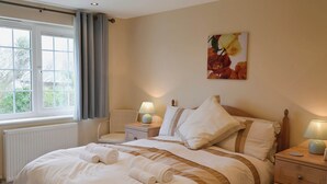 Una cama bien hecha con toallas enrolladas, una lámpara de noche y una mesita de noche.