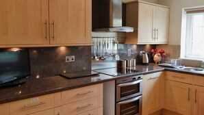 Una cocina moderna con armarios de madera, una campana extractora de acero inoxidable, un horno y un lavavajillas integrado.