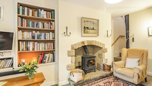 A cozy living room with a fireplace, bookshelves, a comfortable armchair, and a television.