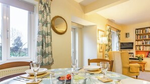 A dining area with a table set for four, a television, and a bookshelf.