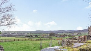 A rural landscape with a stone wall, a wooden fence, and a stone building.