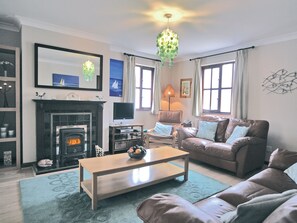 A living room with a fireplace, a television, a sofa, a coffee table, and a chandelier.